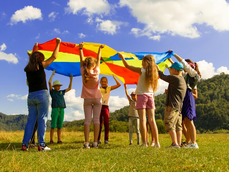 Children playing with a colorful parachute outdoors